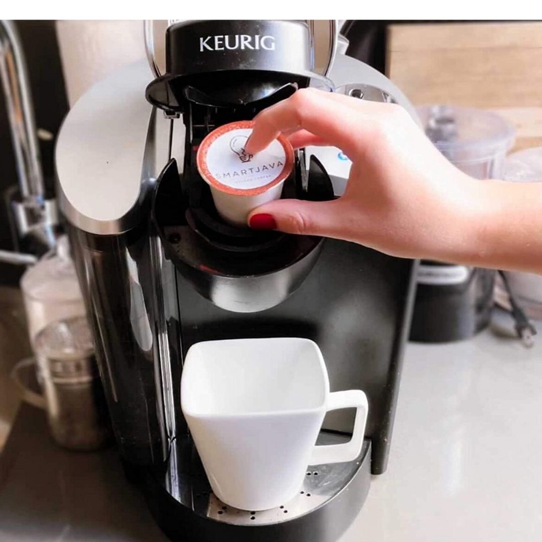 A woman placing a SmartJava coffee pod into a Keurig machine